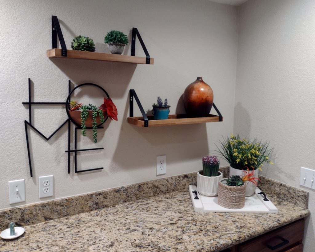 A granite kitchen countertop decorated with a variety of pottery and succulents